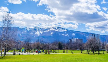 SOFIA, BULGARIA, MARCH 25, 2015: young bulgarians are walking through park in student city in sofia with vitosha mountain on background.