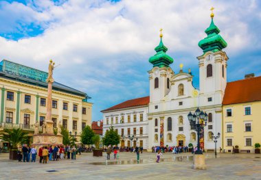 GYOR, HUNGARY 20 Mayıs 2016: Macaristan 'ın Gyor kentindeki Szechenyi Meydanı' ndaki Benedictine Loyolai Szent Ignac Kilisesi önünde insanlar yürüyor