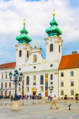 GYOR, HUNGARY 20 Mayıs 2016: Macaristan 'ın Gyor kentindeki Szechenyi Meydanı' ndaki Benedictine Loyolai Szent Ignac Kilisesi önünde insanlar yürüyor