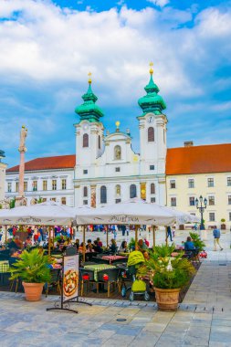 GYOR, HUNGARY 20 Mayıs 2016: Macaristan 'ın Gyor kentindeki Szechenyi Meydanı' ndaki Benedictine Loyolai Szent Ignac Kilisesi önünde insanlar yürüyor