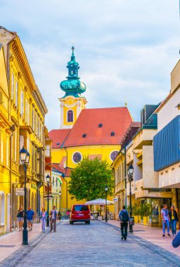 GYOR, HUNGARY 20 Mayıs 2016: Macaristan 'ın eski kenti Gyor' daki dar bir sokaktan Carmelita Kilisesi 'ne doğru yürüyen insanların görüntüsü