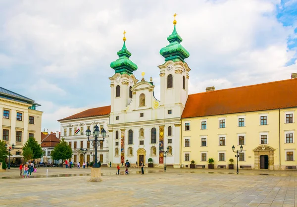 GYOR, HUNGARY 20 Mayıs 2016: Macaristan 'ın Gyor kentindeki Szechenyi Meydanı' ndaki Benedictine Loyolai Szent Ignac Kilisesi önünde insanlar yürüyor
