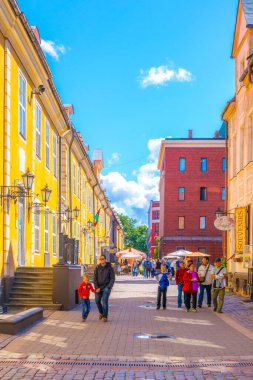 RIGA, LATVIA, 15 AĞUSTOS 2016: İnsanlar eski Letonya 'nın Riga kentindeki renkli bir sokakta yürüyorlar.