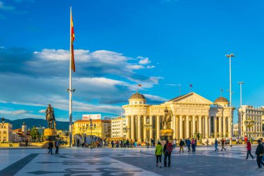 ÜSKÜP, MACEDONIA, 14 Mayıs 2016: Arka planda Macar arkeoloji müzesi bulunan Skopje 'deki Macedonia Meydanı' ndan insanlar geçiyor.