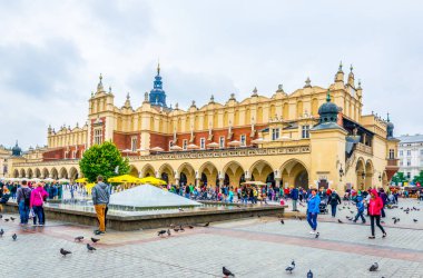 KRAKOW, POLAND, AUGUST 11, 2016: People are strolling in front of the Sukiennice marketplace (Cloth Hall, Drapers' Hall) in Krakow (Cracow), Poland