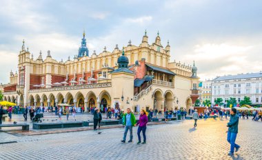 KRAKOW, POLAND, AUGUST 11, 2016: People are strolling in front of the Sukiennice marketplace (Cloth Hall, Drapers' Hall) in Krakow (Cracow), Poland