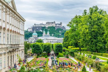 SALZBURG, AUSTRIA, 3 Temmuz 2016: İnsanlar Salzburg, Avusturya 'daki tarihi Hohensalzburg Kalesi' nin arka planında Mirabell Bahçeleri 'nde geziniyorlar