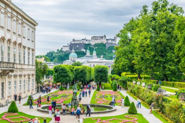 SALZBURG, AUSTRIA, 3 Temmuz 2016: İnsanlar Salzburg, Avusturya 'daki tarihi Hohensalzburg Kalesi' nin arka planında Mirabell Bahçeleri 'nde geziniyorlar