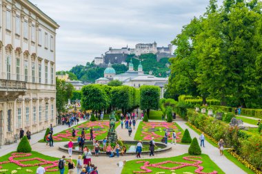 SALZBURG, AUSTRIA, JULY 3, 2016: People are strolling through Mirabell Gardens with the old historic Fortress Hohensalzburg in the background in Salzburg, Austria