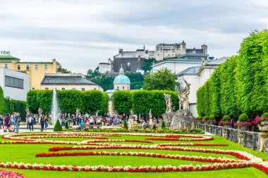 SALZBURG, AUSTRIA, 3 Temmuz 2016: İnsanlar Salzburg, Avusturya 'daki tarihi Hohensalzburg Kalesi' nin arka planında Mirabell Bahçeleri 'nde geziniyorlar