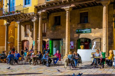 TARRAA, SPAIN, 29 ARALIK 2015: İnsanlar, İspanya 'nın Tarragona şehrinde Aziz Mary katedralinin önündeki bir barda güneşli bir günün tadını çıkarıyorlar.
