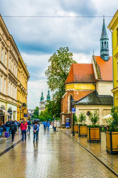 KRAKOW, POLAND, 11 AĞUSTOS 2016: İnsanlar Grodzka caddesinden Krakow / Cracow, Polonya 'daki Aziz Andrew kilisesine doğru yürüyor.