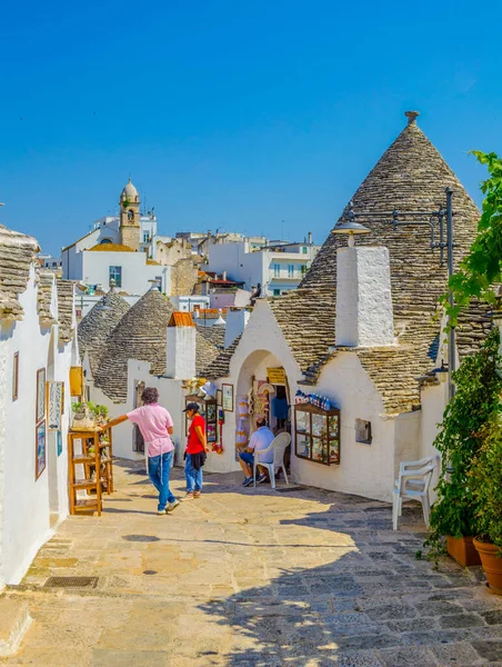 ALBEROBELLO, İtalya, 21 Haziran 2014: Turistler Alberobello, İtalya 'daki trulli evler arasında güneşli bir günün tadını çıkarıyorlar.