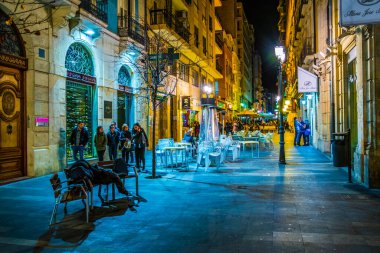 ALICANTE, İspanya, 2 HAZİRAN 2016: İspanya 'nın tarihi kenti Cezayir' de yerel halkın pek çok barın önünde gece hayatının tadını çıkardığı dar bir caddenin görüntüsü.