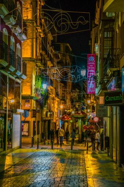 ALICANTE, SPAIN, JANUARY 2, 2016: View of a narrow street in the historical center of spanish city alicante where local people enjoy nightlife in front of many bars.