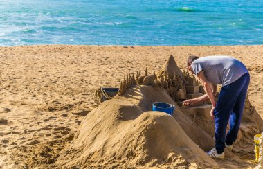 CADIZ, SPAIN, JANUARY 6, 2016: a group of sculptors is preparing a statue of a sand castle on a beach in the spanish city cadiz.