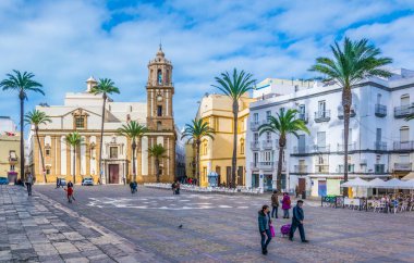 CADIZ, SPAIN, JANUARY 6, 2016: people are crossing plaza de la catedral in front of the church of santiago in spanish city cadiz