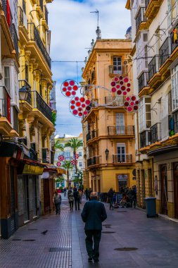 CADIZ, SPAIN, HAZİRAN 6 HAZİRAN 2016: İspanya 'nın tarihi Cadiz kentinde insanlar dar bir caddede çalıyorlar