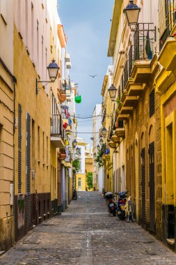 CADIZ, SPAIN, HAZİRAN 6 HAZİRAN 2016: İspanya 'nın tarihi Cadiz kentinde insanlar dar bir caddede çalıyorlar