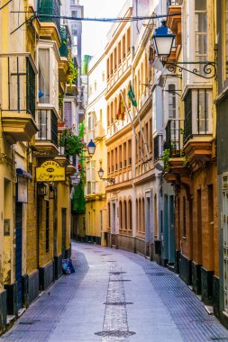 CADIZ, SPAIN, HAZİRAN 6 HAZİRAN 2016: İspanya 'nın tarihi Cadiz kentinde insanlar dar bir caddede çalıyorlar