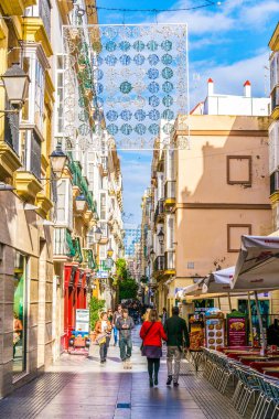 CADIZ, SPAIN, JANUARY 6, 2016: people are stolling through a narrow street in historical center of spanish city cadiz