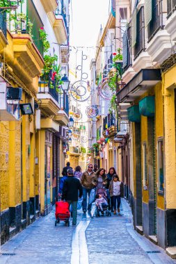 CADIZ, SPAIN, HAZİRAN 6 HAZİRAN 2016: İspanya 'nın tarihi Cadiz kentinde insanlar dar bir caddede çalıyorlar