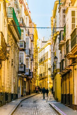CADIZ, SPAIN, HAZİRAN 6 HAZİRAN 2016: İspanya 'nın tarihi Cadiz kentinde insanlar dar bir caddede çalıyorlar