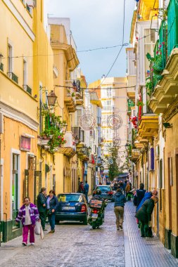 CADIZ, SPAIN, HAZİRAN 6 HAZİRAN 2016: İspanya 'nın tarihi Cadiz kentinde insanlar dar bir caddede çalıyorlar