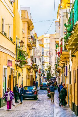 CADIZ, SPAIN, HAZİRAN 6 HAZİRAN 2016: İspanya 'nın tarihi Cadiz kentinde insanlar dar bir caddede çalıyorlar