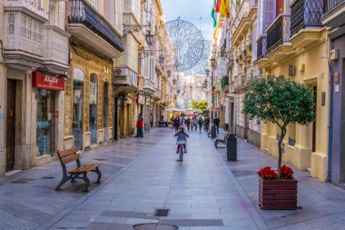 CADIZ, SPAIN, HAZİRAN 6 HAZİRAN 2016: İspanya 'nın tarihi Cadiz kentinde insanlar dar bir caddede çalıyorlar
