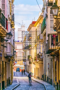 CADIZ, SPAIN, HAZİRAN 6 HAZİRAN 2016: İspanya 'nın tarihi Cadiz kentinde insanlar dar bir caddede çalıyorlar