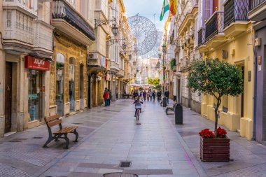 CADIZ, SPAIN, JANUARY 6, 2016: people are stolling through a narrow street in historical center of spanish city cadiz