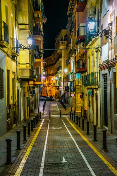 ALICANTE, İspanya, 2 HAZİRAN 2016: İspanya 'nın tarihi kenti Cezayir' de yerel halkın pek çok barın önünde gece hayatının tadını çıkardığı dar bir caddenin görüntüsü.