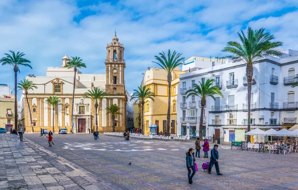 CADIZ, SPAIN, JANUARY 6, 2016: İspanya 'nın Cadiz kentindeki Santiago Kilisesi önünde insanlar plaza de la kategorisinden geçiyorlar