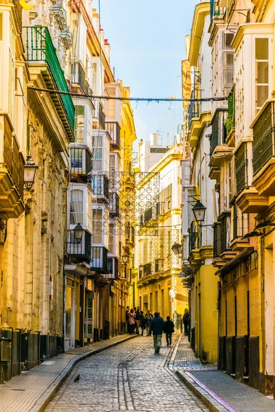 CADIZ, SPAIN, HAZİRAN 6 HAZİRAN 2016: İspanya 'nın tarihi Cadiz kentinde insanlar dar bir caddede çalıyorlar