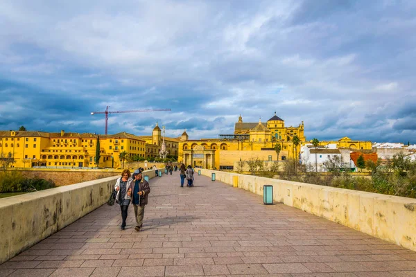 CORDOBA, SPAIN, HAZİRAN 8 HAZİRAN 2016: İspanya 'nın Cordoba kentindeki Roma köprüsünden geçerek La mezquita katedraline doğru yürüyorlar.