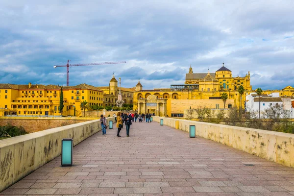 CORDOBA, SPAIN, HAZİRAN 8 HAZİRAN 2016: İspanya 'nın Cordoba kentindeki Roma köprüsünden geçerek La mezquita katedraline doğru yürüyorlar.