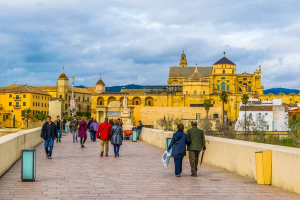 CORDOBA, SPAIN, HAZİRAN 8 HAZİRAN 2016: İspanya 'nın Cordoba kentindeki Roma köprüsünden geçerek La mezquita katedraline doğru yürüyorlar.