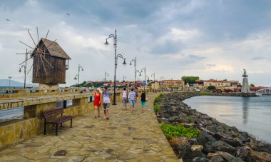 NESSEBAR, BULGARIA, 14 Temmuz 2015: İnsanlar Bulgaria 'daki Unesco Dünya Mirası Şehir Nessebar' ına giderken eski bir yel değirmeninin önünden geçiyorlar.
