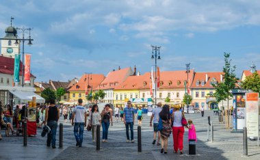 SIBIU, ROMANIA, 6 HAZİRAN 2015: İnsanlar Nicolae Balcescu bulvarı boyunca yürüyor ya da Büyük Meydan 'da güneşli bir günün tadını çıkarıyorlar, üst şehrin en büyük meydanı ve UNESCO tarafından yapılmış bir mimari anıt..
