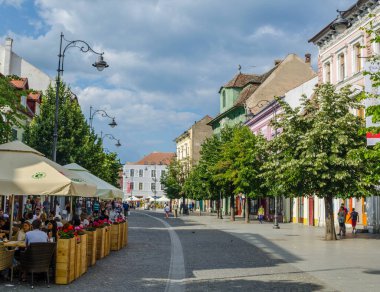 SIBIU, ROMANIA, JULY 6, 2015: people stroll along the boulevard nicolae balcescu or enjoy a sunny day in the Great Square, the largest square in the upper town and an architectural monument by UNESCO.
