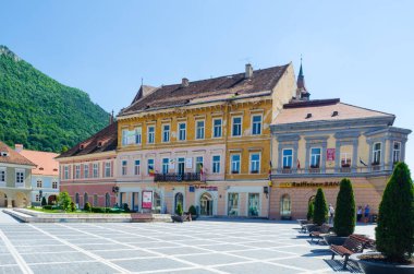BRASOV, ROMANIA, 6 Temmuz 2015: Council Square şehrin tarihi merkezidir, insanlar açık teras ve restoranlarda yürüyor ve oturuyorlar.