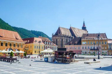 BRASOV, ROMANIA, 6 Temmuz 2015: Council Square şehrin tarihi merkezidir, insanlar açık teras ve restoranlarda yürüyor ve oturuyorlar.