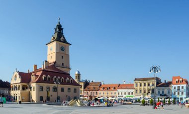 BRASOV, ROMANIA, 6 Temmuz 2015: Council Square şehrin tarihi merkezidir, insanlar açık teras ve restoranlarda yürüyor ve oturuyorlar.