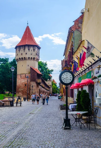 SIBIU, ROMANIA, 6 HAZİRAN 2015: Ortaçağ savunma duvarı ve Transilvanya 'nın Transilvanya bölgesindeki Marangoz Kulesi boyunca dolaşan kimliği belirsiz kişiler.