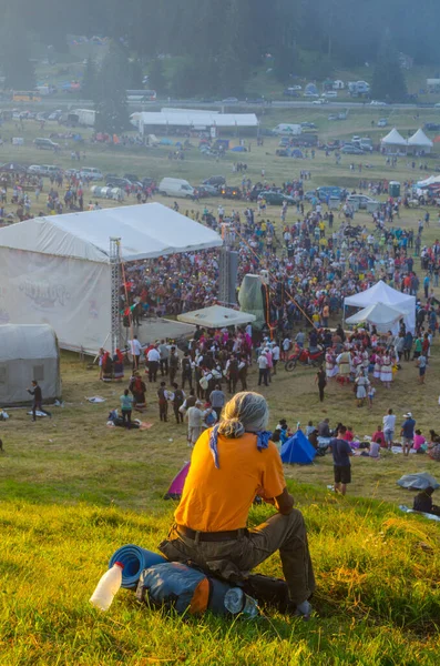 ROZHEN, BULGARIA, 18 HAZİRAN 2015: Sırt çantasında bir tepede oturan bir adam ve Rozhen folklor festivalini Bulgaristan 'da Rozhen folklor dağlarında izleyen insanlardan oluşan bir kalabalık görülüyor.