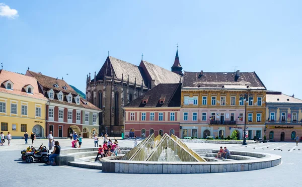 BRASOV, ROMANIA, 6 Temmuz 2015: Council Square şehrin tarihi merkezidir, insanlar açık teras ve restoranlarda yürüyor ve oturuyorlar.