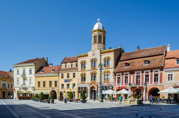 BRASOV, ROMANIA, 6 Temmuz 2015: Council Square şehrin tarihi merkezidir, insanlar açık teras ve restoranlarda yürüyor ve oturuyorlar.