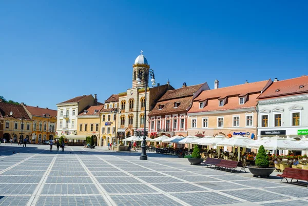BRASOV, ROMANIA, 6 Temmuz 2015: Council Square şehrin tarihi merkezidir, insanlar açık teras ve restoranlarda yürüyor ve oturuyorlar.