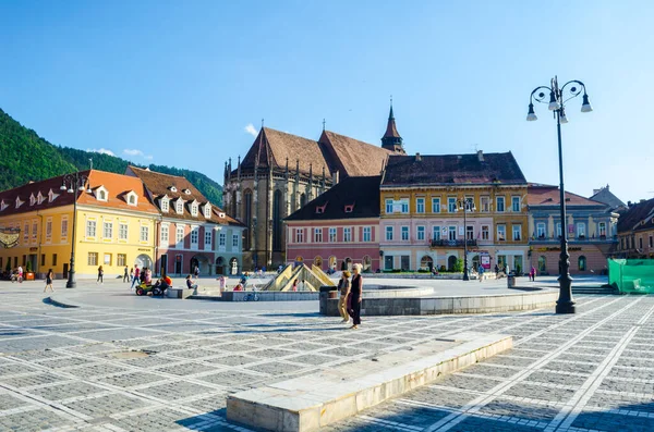 BRASOV, ROMANIA, 6 Temmuz 2015: Council Square şehrin tarihi merkezidir, insanlar açık teras ve restoranlarda yürüyor ve oturuyorlar.